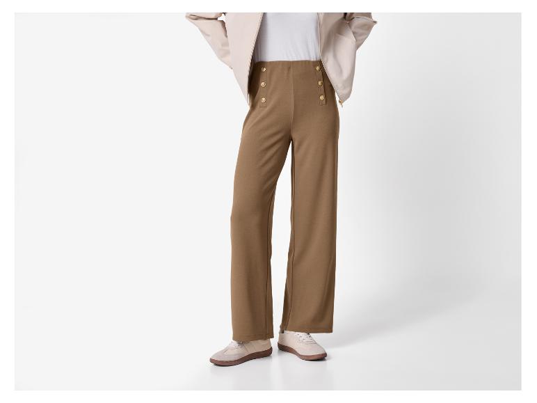 Braune weite Hose mit goldenen Knöpfen und beigen Sneakern.