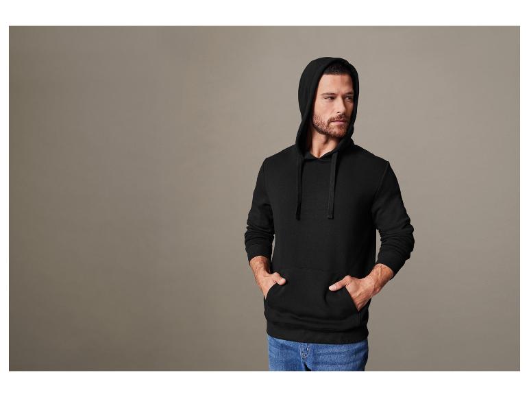Ein Mann trägt einen schwarzen Hoodie.
