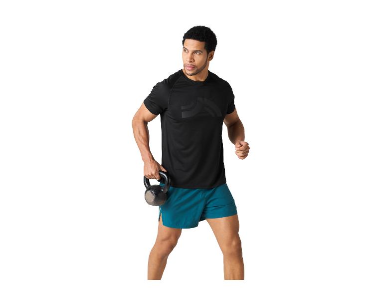 Ein Mann in schwarzem T-Shirt und blauen Shorts hält eine Kettlebell.