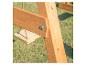 Detail einer Holzkonstruktion mit Schraube, im Hintergrund eine Schaukel und Gras.