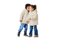 Zwei Kinder in cremefarbenen Pufferjacken und Jeans, eines flüstert dem anderen zu.
