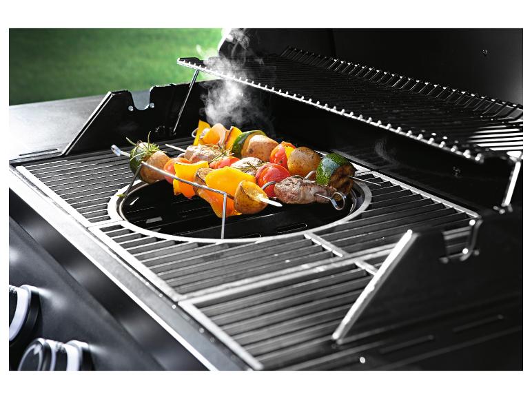 Grill mit offenem Deckel und Spießen mit Fleisch und Gemüse, aus denen Dampf aufsteigt.