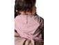 Baby in rosa Sweatshirt mit Knöpfen am Rücken.