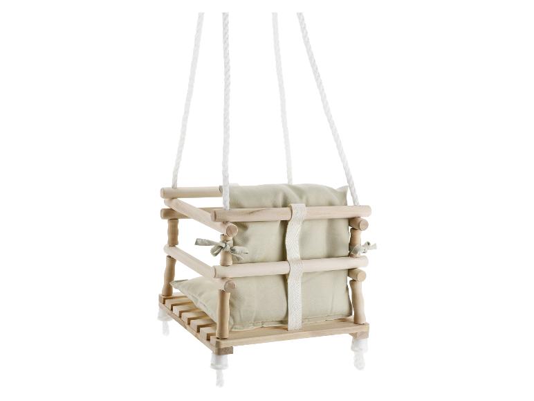 Holz-Babyschaukel mit beigen Kissen, aufgehängt an weißen Seilen.