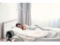 Frau schläft im Bett mit einem Ventilator auf dem Nachttisch