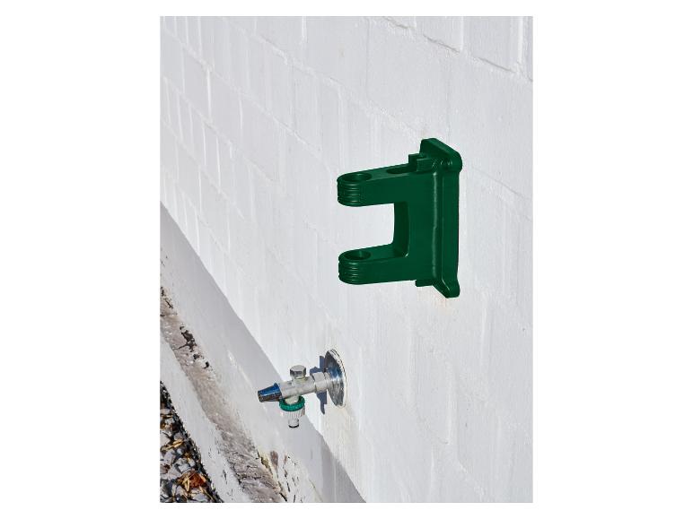 Grüne Wandhalterung für Gartenschlauch mit Wasserhahn darunter.