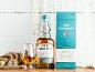 Eine Flasche Single Malt Whisky und ein Glas, mit Kompass und Seil, auf einer Holzoberfläche.