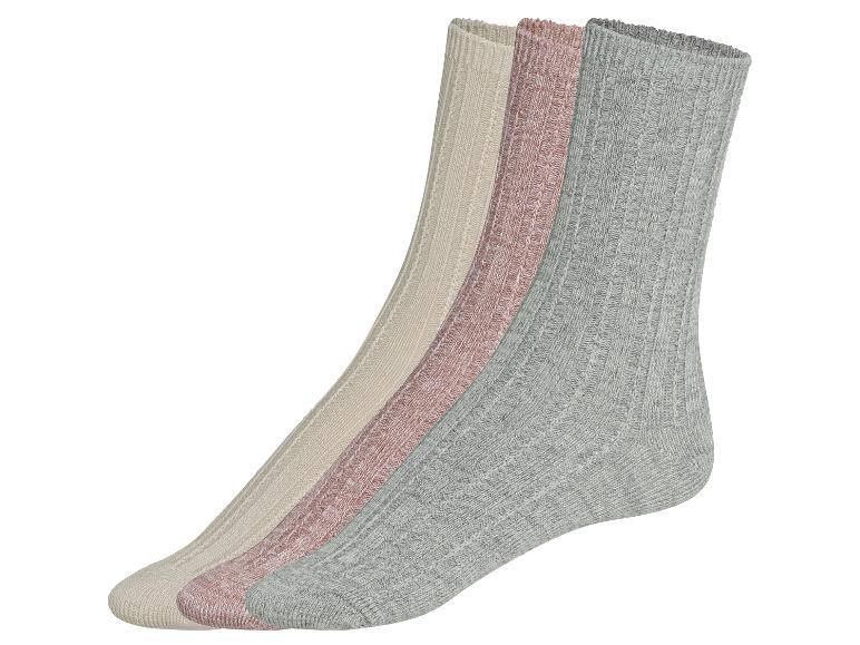 Drei Paar gestrickte Socken in Beige, Rosa und Grau.