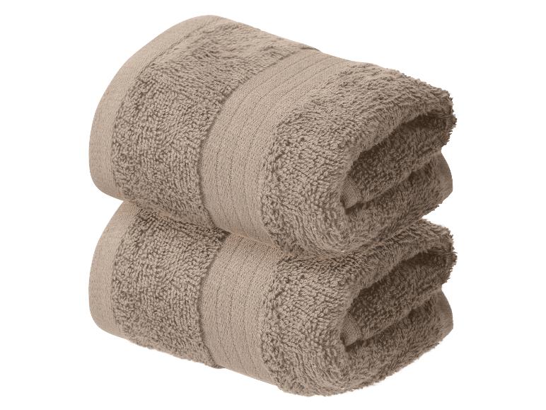 Zwei gefaltete braune Handtücher auf weißem Hintergrund