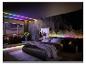 Modernes Schlafzimmer mit Bett, Badewanne und farbiger LED-Streifenbeleuchtung.