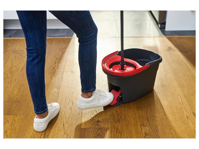 Person in Jeans und weißen Schuhen benutzt einen Wischmopp mit Pedaleimer.