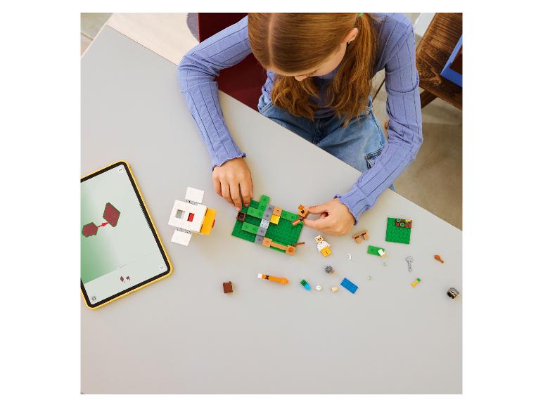 Mädchen baut Spielzeug aus Bausteinen, mit Anleitung auf einem Tablet.