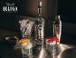 Wodkaflasche, Eiseimer, Cocktailshaker und zwei Cocktails mit Garnituren auf einer Metalloberfläche.