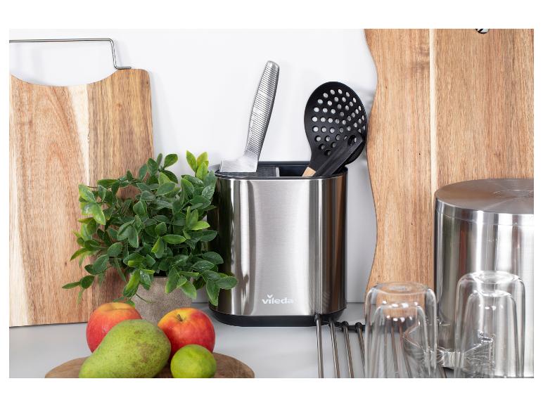 Küchenutensilien aus Edelstahl und Holzschneidebretter mit Obst.