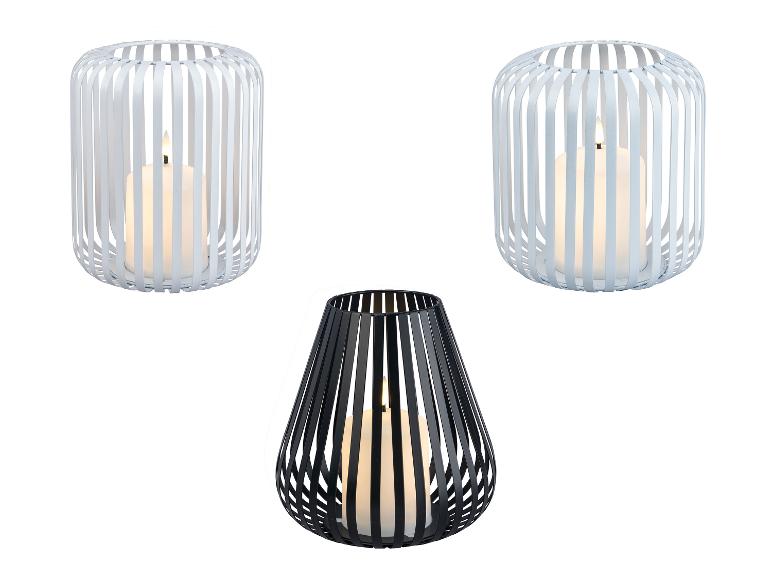 Drei Laternen mit Kerzen: zwei weiße zylindrische und eine schwarze tropfenförmige.