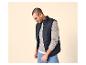 Mann in dunkelblauer Steppweste, hellgrauem Pullover und blauer Jeans.