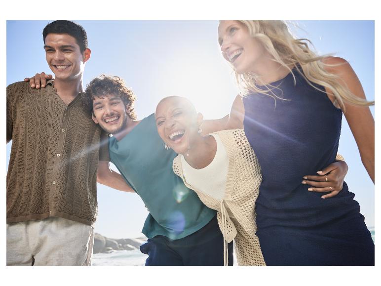 Lachende Freunde in Freizeitkleidung am Meer.