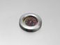 Ein Thermometer in einem Metallgehäuse auf einem Grill.