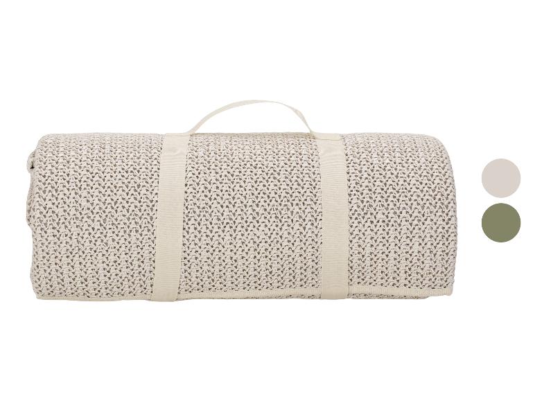 Gerollte beige Strickdecke mit Griff und Farbmustern.