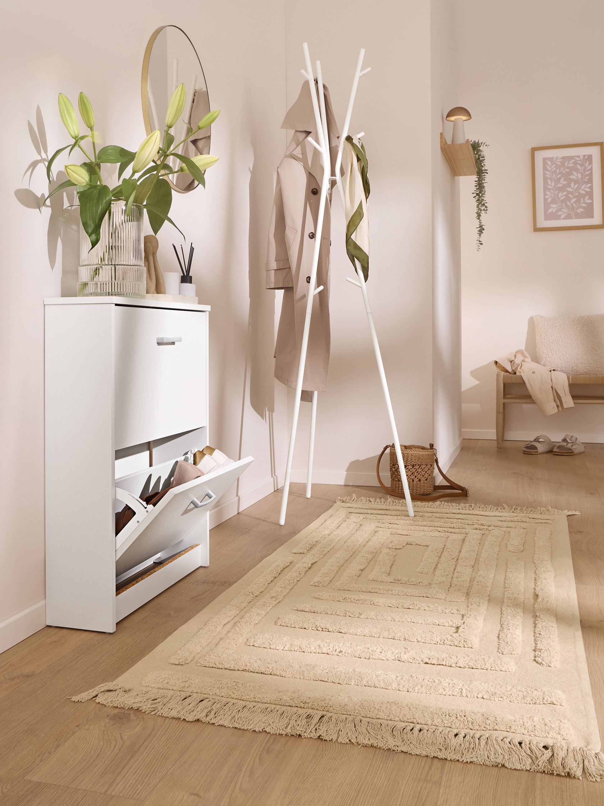 Flur mit weißem Schuhschrank, Garderobe und beigem Teppich.