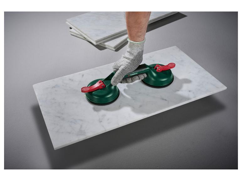 Arbeiter hebt mit Saugnäpfen eine weiße Marmorplatte an.