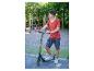 Junger Junge in rotem T-Shirt und gemusterten Shorts, steht mit einem schwarz-gelben Roller.