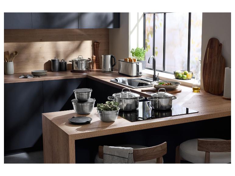 Moderne Küche mit Edelstahl-Kochgeschirr, Toaster und Wasserkocher auf Holz-Arbeitsplatten.