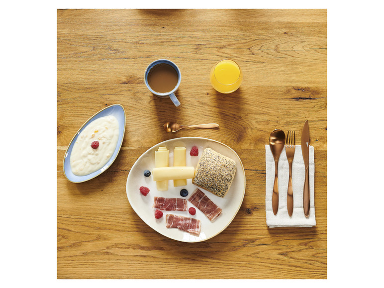 Ein Frühstück mit Käse, Brot, Schinken, Joghurt und Orangensaft.