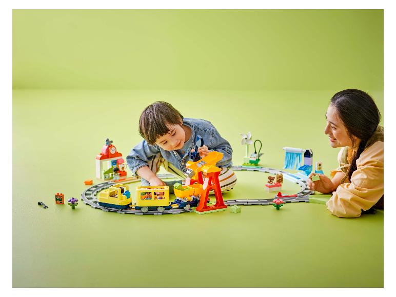 Ein Kind und ein Erwachsener spielen mit einem Spielzeugzug und Bausteinen.