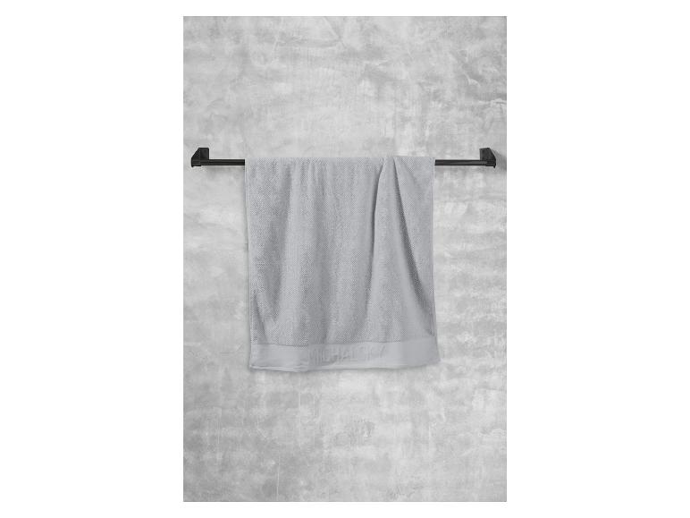 Ein graues Handtuch der Marke Michaelsky hängt an einer schwarzen Handtuchhalterung.