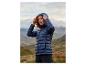 Frau mit roten Locken trägt eine dunkelblaue Steppjacke in einer Berglandschaft.