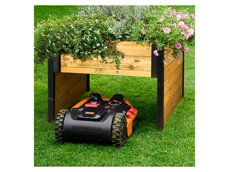 Mähroboter unter einem Hochbeet mit Blumen auf dem Rasen.