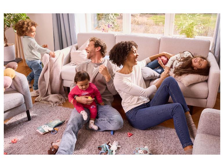 Eine glückliche Familie spielt zu Hause, umgeben von Babyspielzeug.