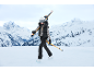 Eine Frau in stilvoller Skikleidung läuft mit Skiern und Stöcken auf einem verschneiten Berg.