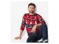 Mann in einem roten Weihnachtspullover mit Schneemann- und Tannenbaum-Motiven, auf dem Boden sitzend.