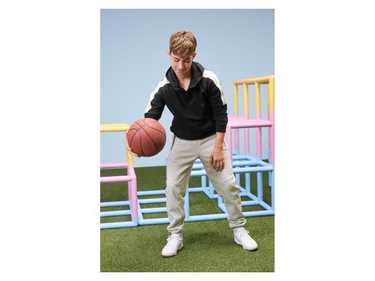 Junge in einem ESMARA KIDS Kinder-Sweathoodie dribbelt mit einem Basketball.