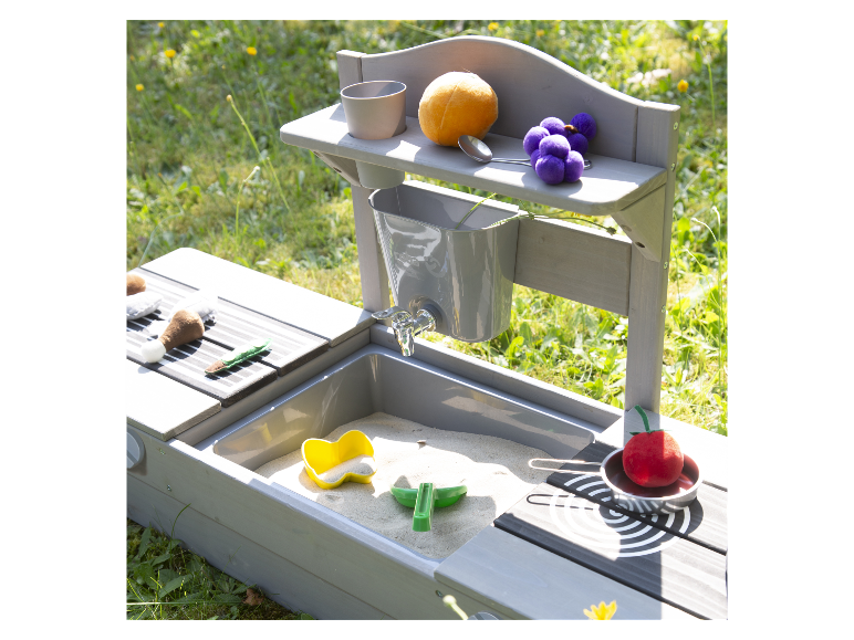 Kinderspielplatz mit Sandkasten und Spielküche, gefüllt mit Spielzeugessen.