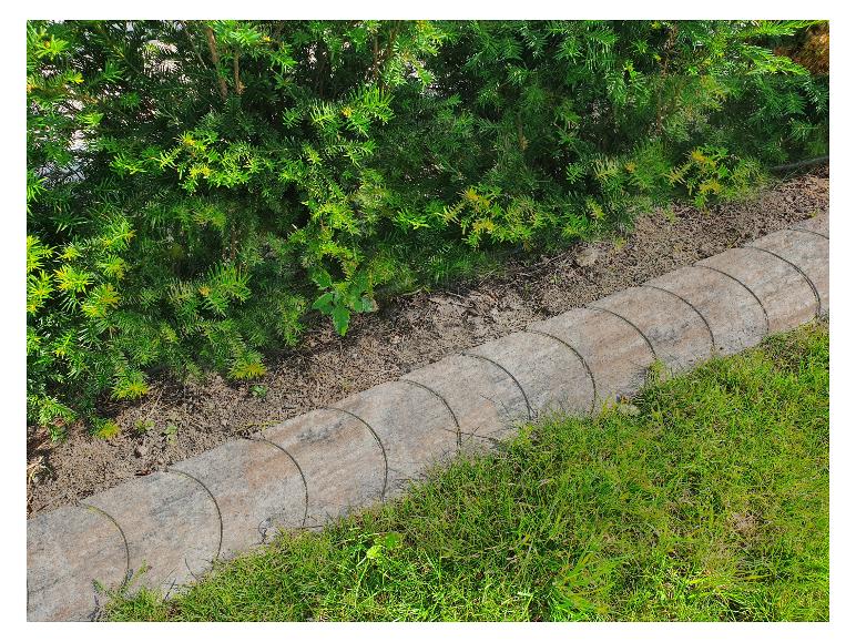 Grüne Hecke und Rasen, getrennt durch eine Steinumrandung