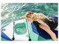 Frau auf einem Stand-Up-Paddleboard mit Sichtfenster, Hand im Wasser.