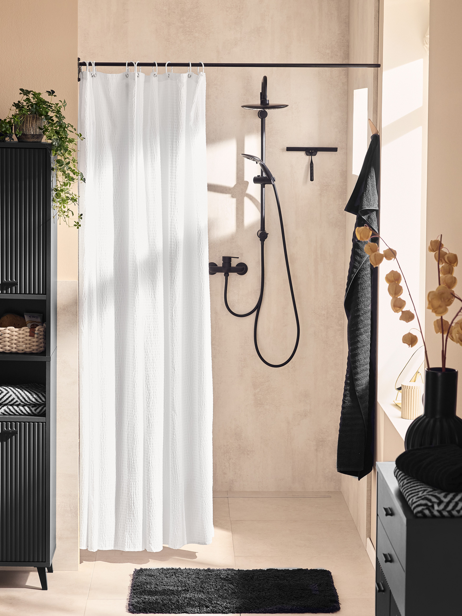 Modernes Badezimmer mit schwarzem Schrank, weißem Duschvorhang und schwarzem Badteppich.