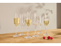 Sechs Sektgläser, einige mit Sekt gefüllt, und drei Himbeeren auf einem Holztisch.