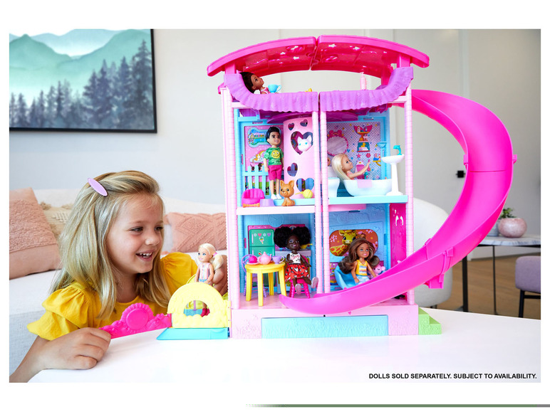 Ein rosafarbenes Barbie Puppenhaus mit Rutsche und mehreren Puppen.