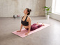 Frau macht Yoga auf einer rosa Matte.
