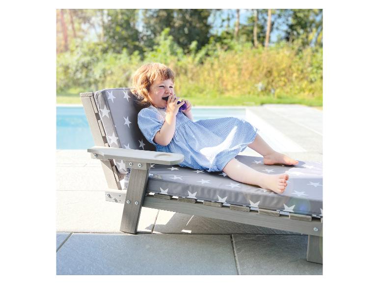 Kleinkind in blauem Kleid entspannt auf einer Liege mit Sternenmuster am Pool.