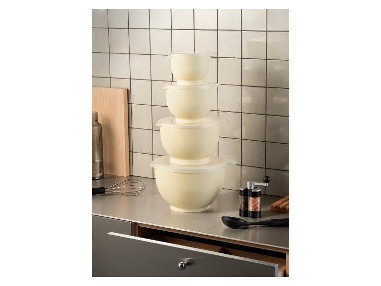 Gestapelte cremefarbene Rührschüsseln mit Deckeln auf einer Küchenarbeitsplatte mit Schneebesen und Gewürzmühle.