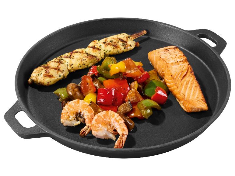 Gegrillter Hähnchenspieß, Lachsfilet, Garnelen und bunte Paprika in einer schwarzen Pfanne.