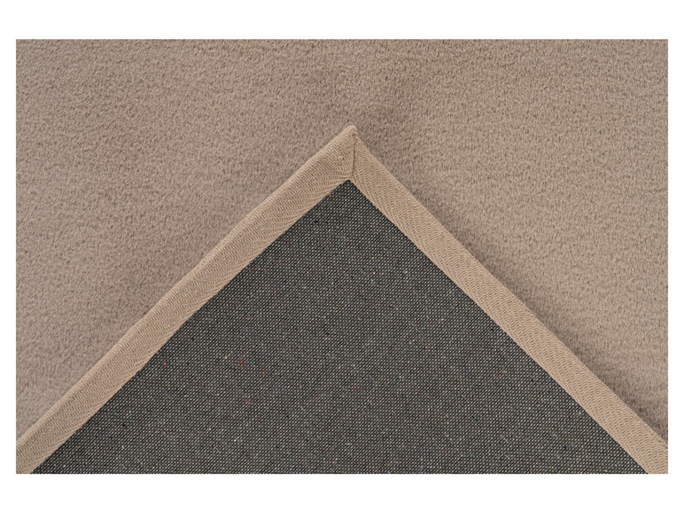 Ein beiger Teppich mit einer dunkelgrauen Unterseite.