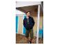 Mann in marineblauer Jacke, gestreiftem T-Shirt und Cargoshorts am Sandstrand.