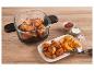 Glas-Heißluftfritteuse mit Hähnchenflügeln und Kartoffelspalten, Ketchup und Salz auf einem Holztisch.