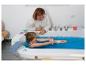 Frau und Kind spielen mit einer Puppe in einer Badewanne mit blauem Wasser.